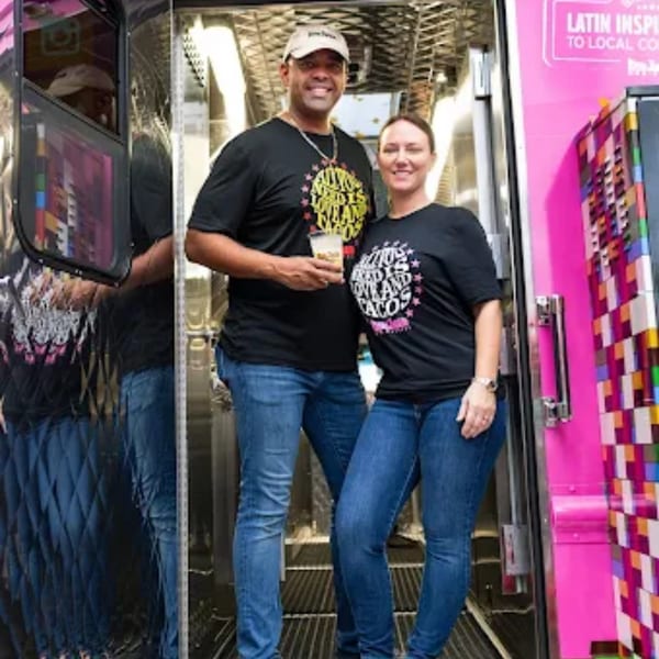 Two Don Juan Mex Grill owners, a man and a woman, stand smiling inside a food truck.