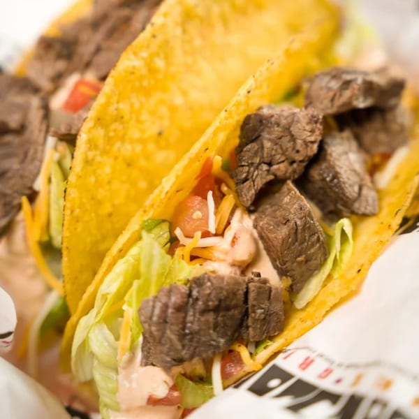 Two crispy tacos filled with steak, lettuce, cheese, tomatoes, and creamy sauce from Don Juan Mex Grill.