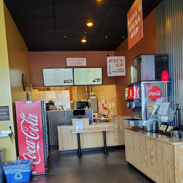 Interior of Don Juan Mex Grill, showing the order counter, menu boards, soda fountain, and a Coca-Cola fridge.