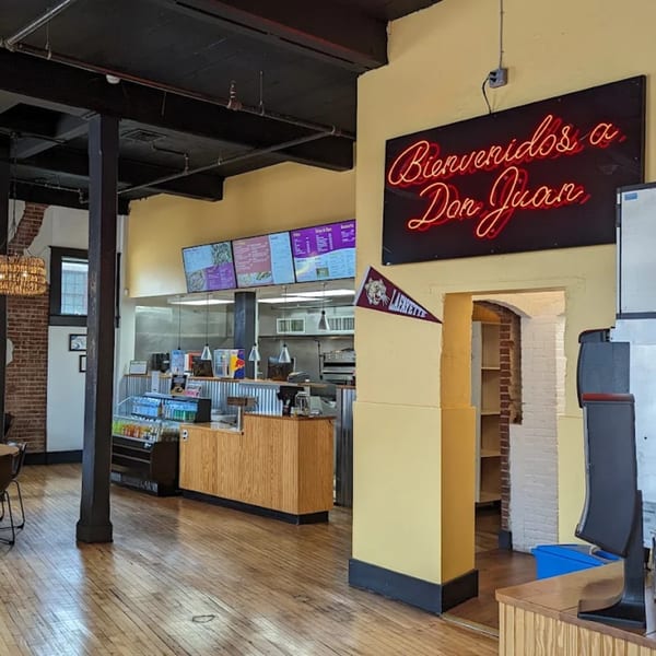 Interior of Don Juan Mex Grill with a neon "Bienvenidos a Don Juan" sign and ordering counter.