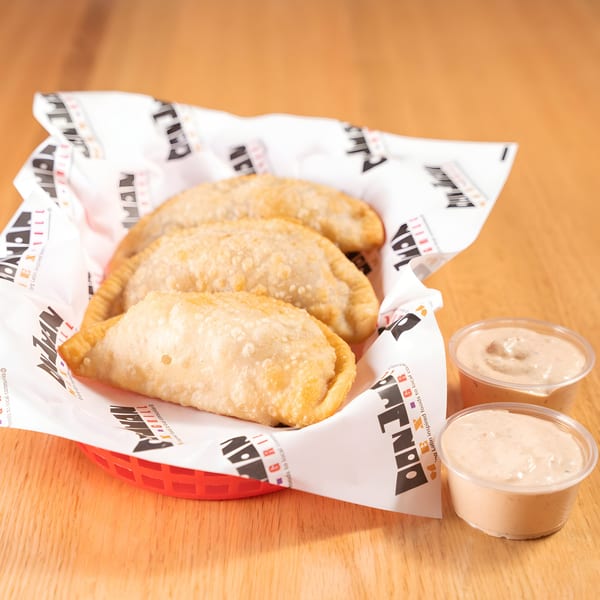 Three golden-brown Don Juan Mex Grill empanadas in a red basket with two dipping sauces.