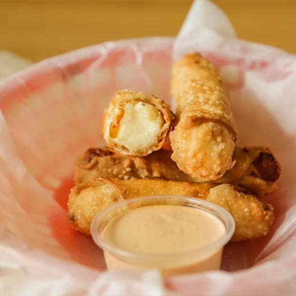 Don Juan Mex Grill's crispy fried taquitos with a creamy dipping sauce in a red basket.