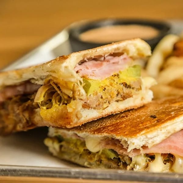 Close-up of a Don Juan Mex Grill Cuban sandwich, cut in half, with melted cheese and ham.