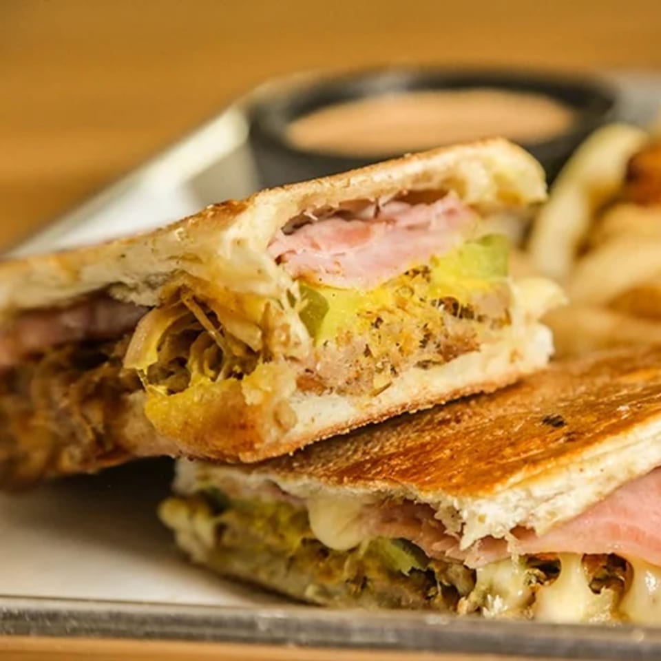 Close-up of a Don Juan Mex Grill Cuban sandwich, cut in half, with melted cheese and ham.