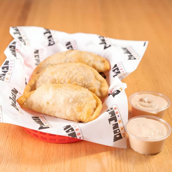 Three golden-brown Don Juan Mex Grill empanadas in a red basket with two dipping sauces.