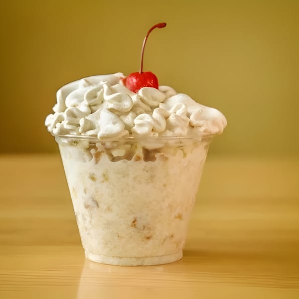 A Don Juan Mex Grill dessert cup filled with creamy white dessert, topped with whipped cream and a cherry.