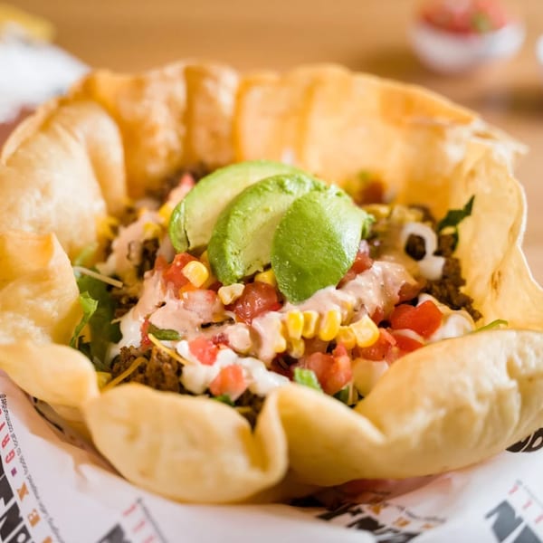 Don Juan Mex Grill taco salad in a crispy tortilla bowl with ground beef, avocado, and salsa.