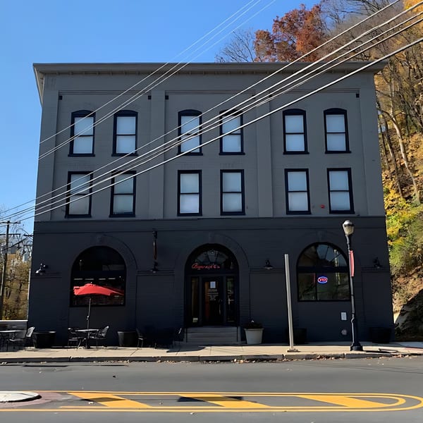Don Juan Mex Grill's gray and dark gray brick building with arched windows and a red umbrella.