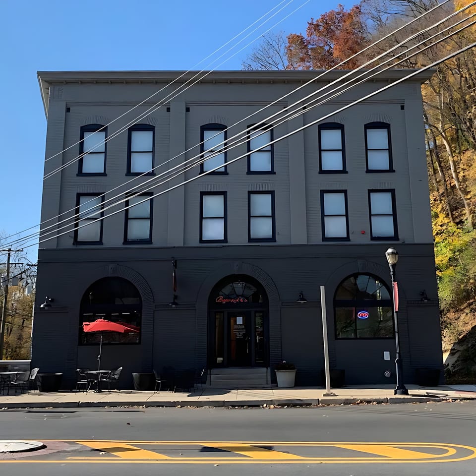 Don Juan Mex Grill's gray and dark gray brick building with arched windows and a red umbrella.