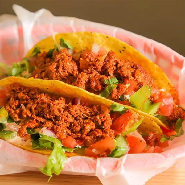 Two crispy Don Juan Mex Grill tacos filled with seasoned meat, lettuce, and diced tomatoes.