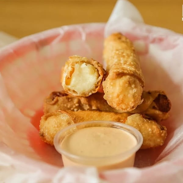 Don Juan Mex Grill's crispy fried taquitos with a side of creamy dipping sauce in a red basket.